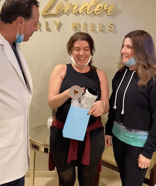 Woman in doctor's office with doctor, female companion, holding a blue goodie bag. 